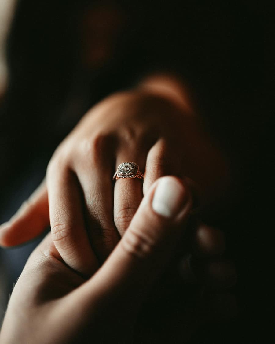 A diamond halo ring being eased onto someone's ring finger